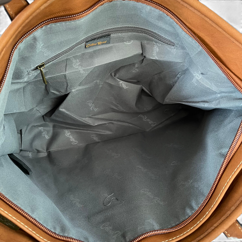 Cotton Road Handbag in brown PU leather, showing a spacious grey lined interior with a zip pocket and branding.