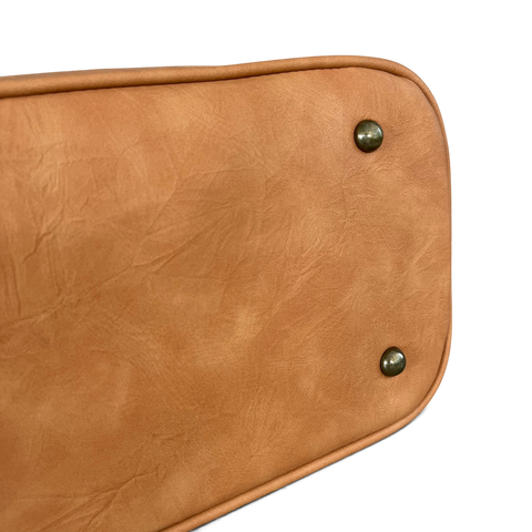 Cotton Road Handbag in tan PU leather, showing a smooth base with rounded edges and metal feet