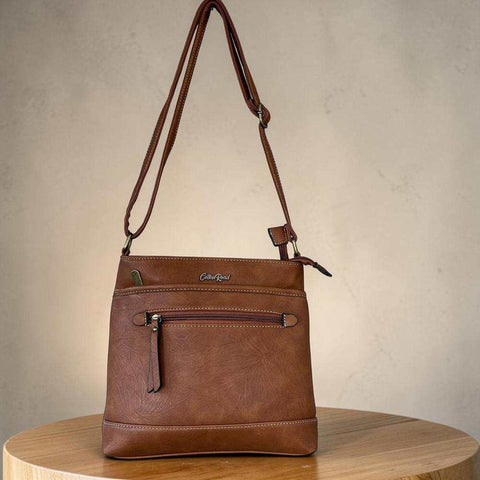 Cotton Road Sling Bag in brown PU leather with contrast stitching, front zip pocket and adjustable crossbody strap