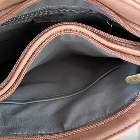 Cotton Road Sling Bag in pink PU leather, showing a lined interior with multiple zip compartments and branding