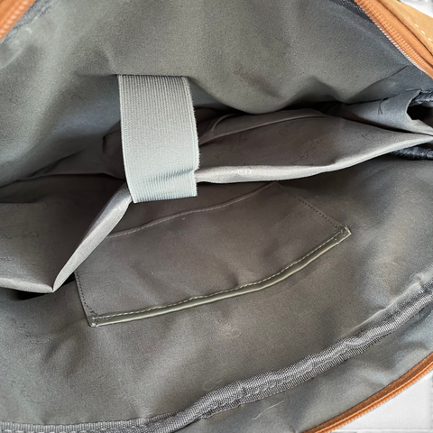 Cotton Road Laptop Bag in khaki PU leather, showing a dark lined interior with padded laptop sleeve and securing strap