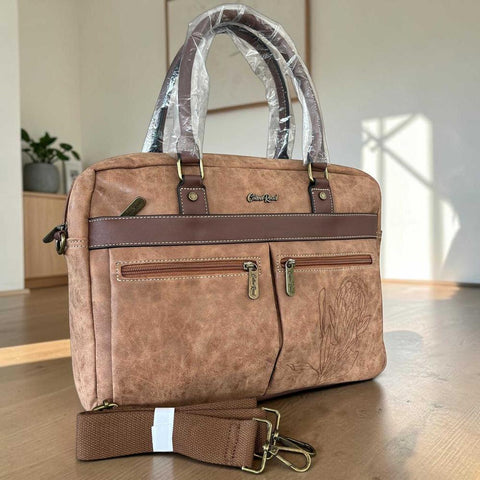 Cotton Road Laptop Bag in brown PU leather with twin handles, front zip pockets and Protea floral embossing